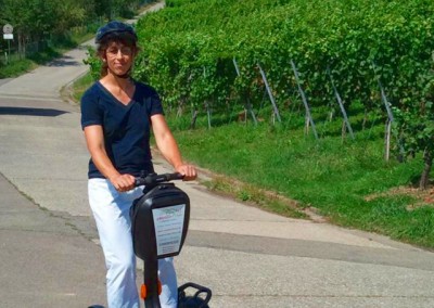 SEGWAY Fahrerin auf SEGWAY vor einem Weinberg