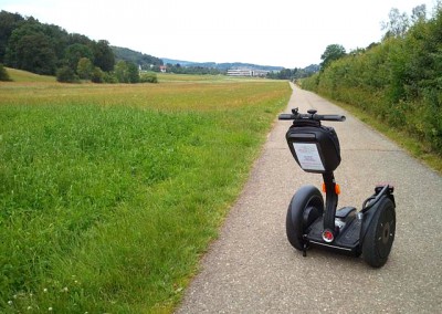 SEGWAY auf Radweg entlang der Bahnlinie mit Krankenhaus Münsingen im Hintergrund